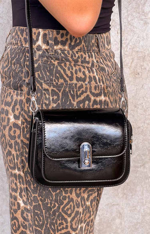 Girl wearing a leopard jeans and a black crossbody bag with silver hardware