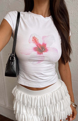 Model wearing a white hibiscus tee with white ruffle shirts