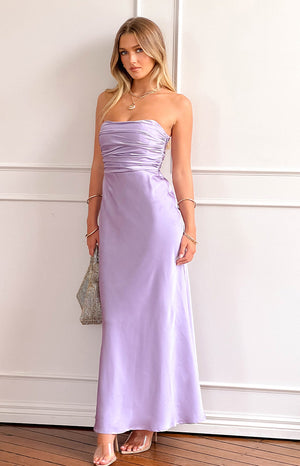 blonde model wearing a lilac strapless maxi dress with nude heels, gold and silver jewellery and a sparkly shoulder bag