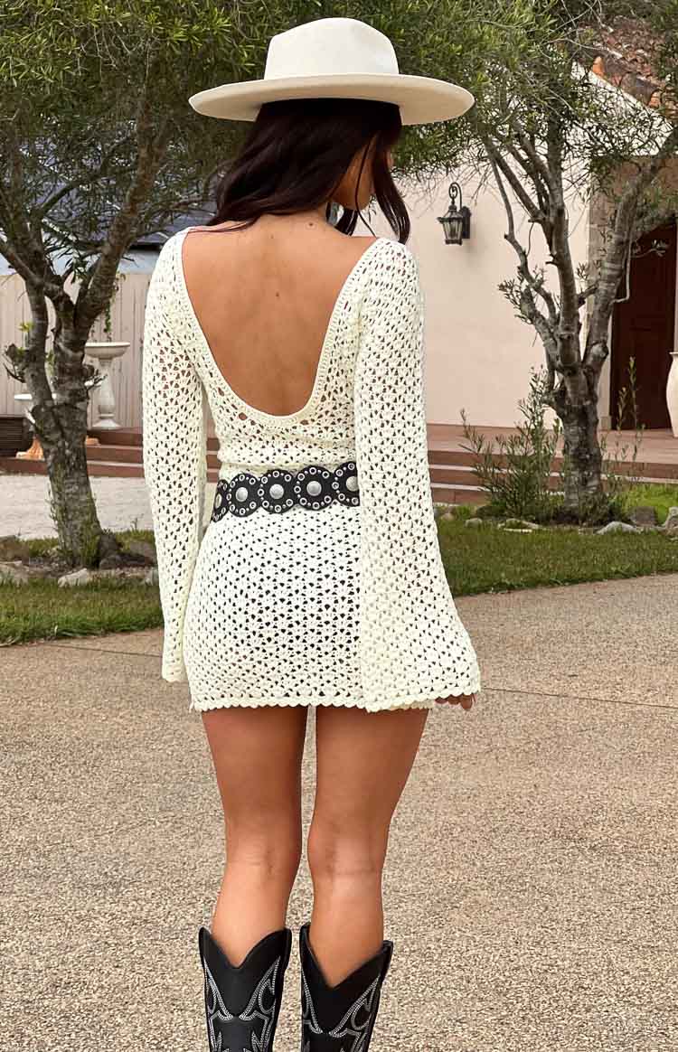 White long sleeve crochet mini dress with silver belt, cowboy boots, and a felt wide brimmed hat on brunette model.