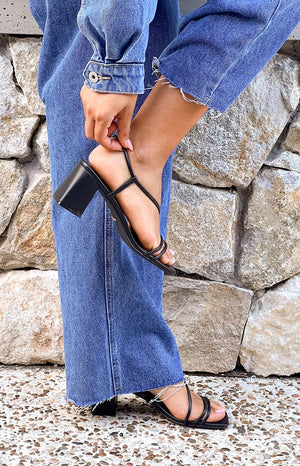 Model wearing black block heels and denim jeans and denim jacket. 