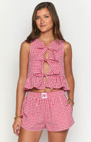 Model in red gingham top with bows with matching red gingham shorts looking to the side. 