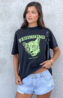 Model wearing a washed black oversized graphic tee with a green lion cub and the word 