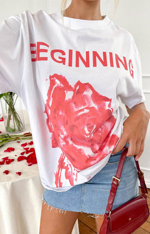 a white printed t-shirt with a pink rose and the word 'beginning' paired with a denim mini skirt and red purse worn by a blonde girl