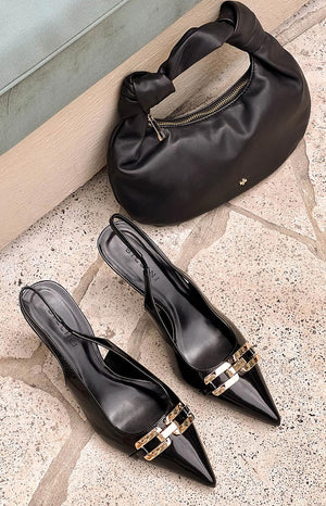 pinterest style flat lay of black and silver pointed toe heels and a black twist strap shoulder bag