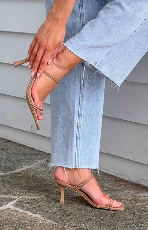 Light wash blue jeans and nude heels with two straps.