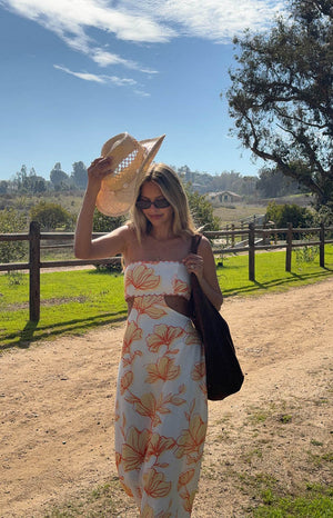 model is wearing a orange, yellow and white floral strapless maxi dress with side cutout details