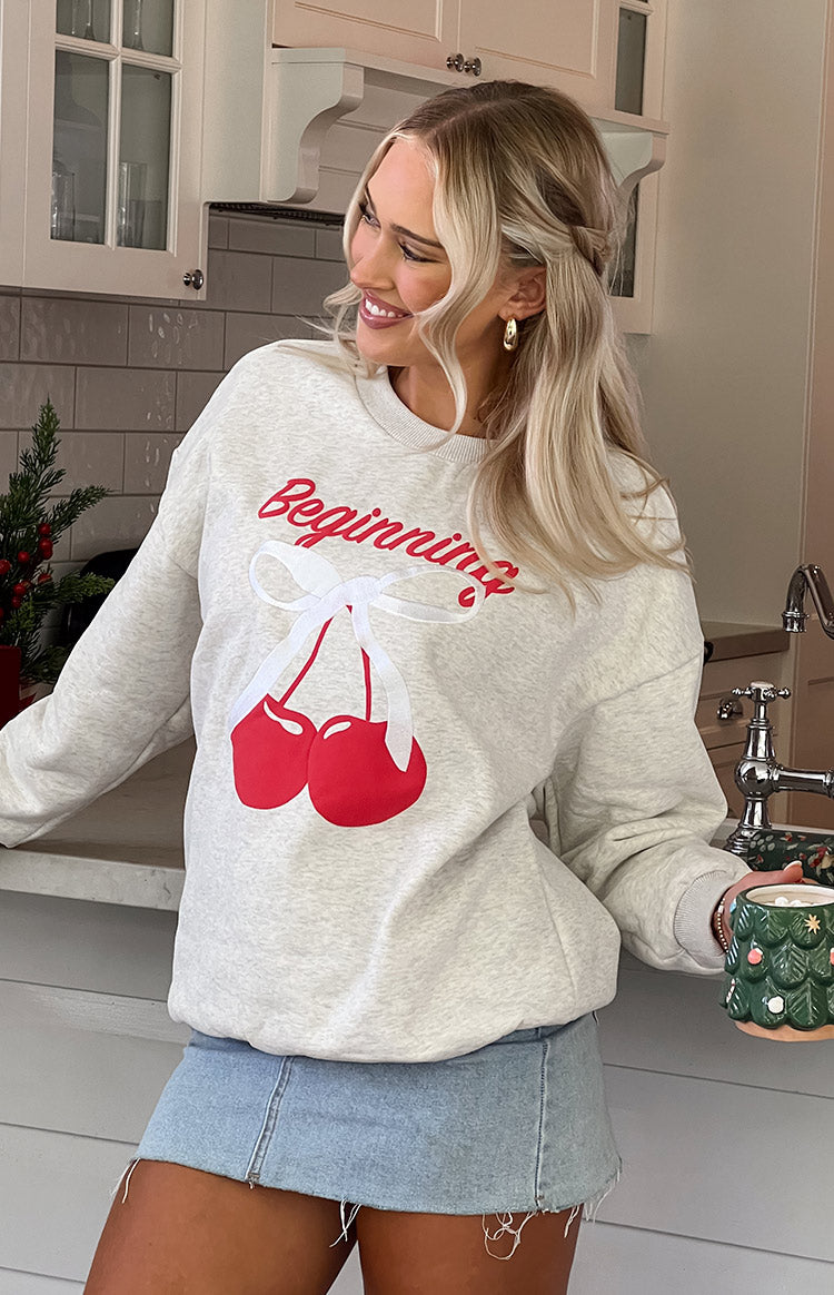 Blonde model wearing grey cherry sweater and denim mini skirt holding a christmas mug.