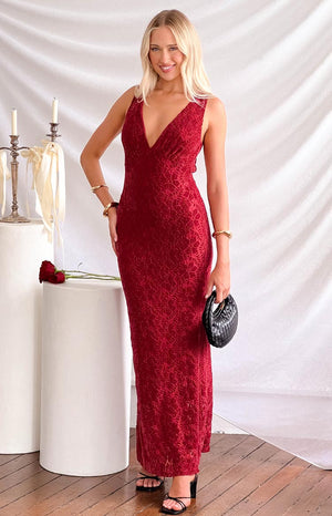 a blonde model a red maxi dress with black heels, gold bracelets and a black purse