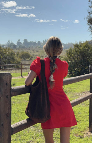 girl is wearing a red mini dress with short puff sleeves paired with a brown bag 