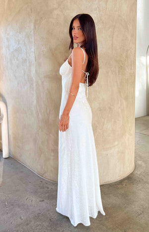 Girl wearing white maxi dress and gold bracelets.