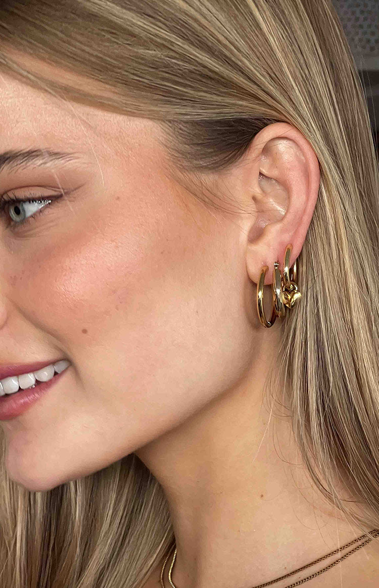 Side profile of blonde girl wearing three gold hoop earrings.