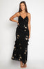 brunette model wearing a black maxi dress with sequin flower detail, gold necklace, gold bracelet and black heels 