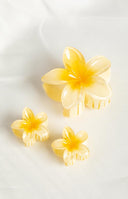 Close up of model with brunette hair, she is wearing three yellow frangipani hair clips in her hair to hold it back. 