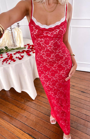 a red and white lace dress is worn by a blonde model with gold bracelets and white heels