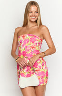 Model is wearing a bright pink and yellow floral print strapless mini dress with gold jewellery.