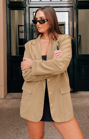 Brown tan oversized blazer worn with black sunglasses and black strapless mini dress.