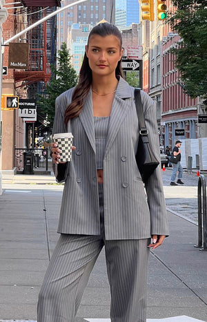 Brunette girl in grey striped blazer, matching top and pants on street