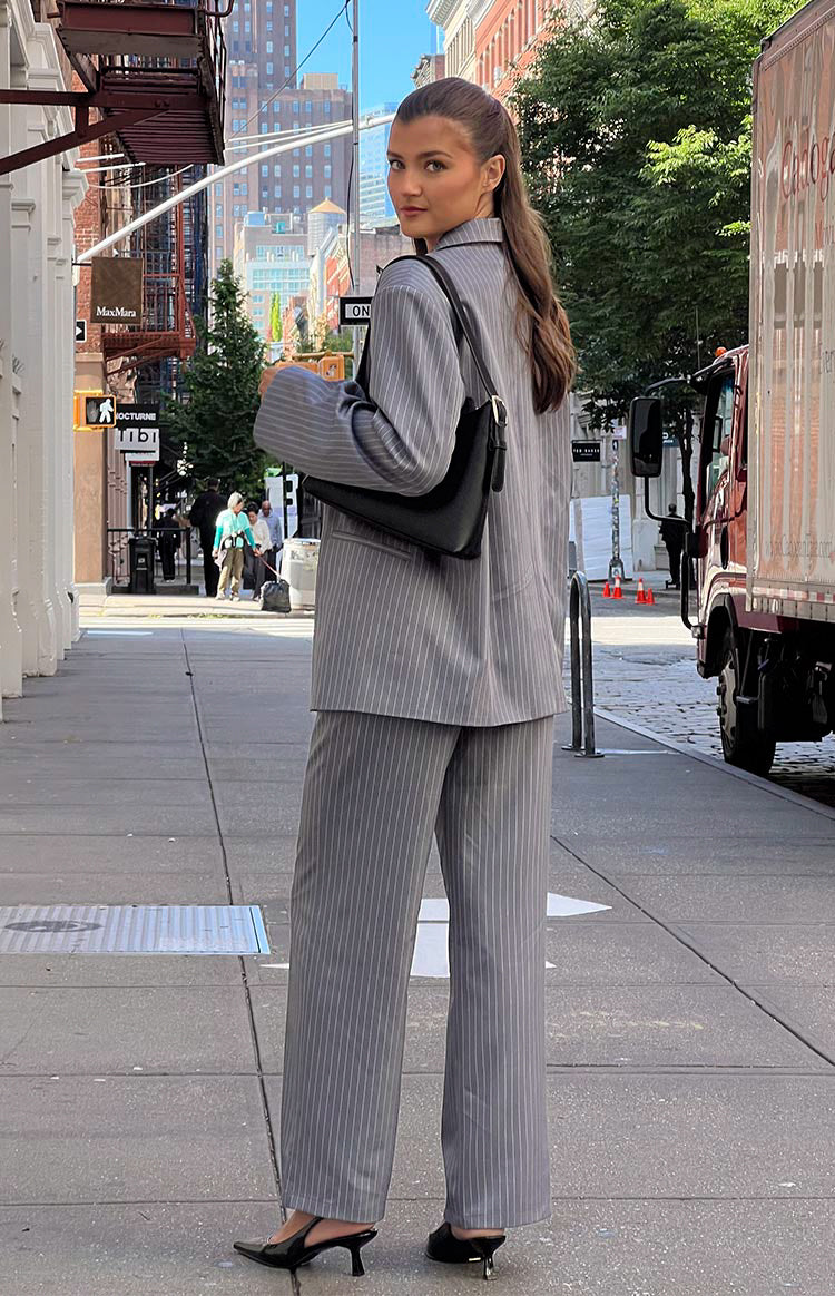 Brunette girl in grey striped pants looking over shoulder on street