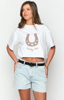 Close up of girl wearing a white western tee, black belt, denim shorts and black boots.