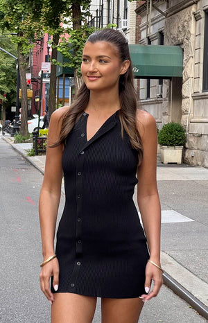 Brunette model wearing black button up mini dress on the street. 