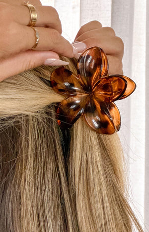 blonde girl wearing a brown tortoise shell flower claw clip and delicate gold rings