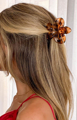 blonde model wearing a brown tortoise shell flower claw clip with a red dress and delicate gold chain necklace