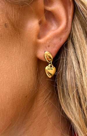 girl wearing a dangle thick gold heart stud earrings