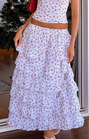 Girl wearing white christmas print maxi skirt and top with beige heels and red bag.