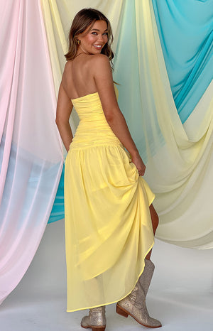 Girl looking back in a yellow strapless maxi dress and silver cowboy boots.