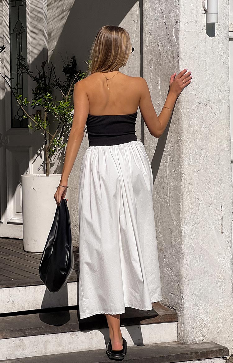 Girl facing away wearing flowy maxi dress and black handbag.