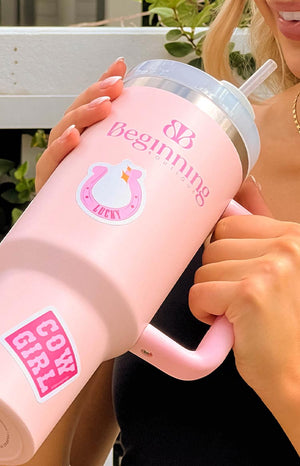 girl holding sticker sheet with assorted pink designs and sticking them onto a pink metal water bottle