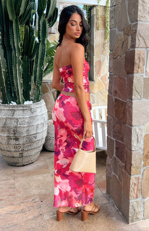 Model posing over her shoulder, shown outside wearing a pink printed maxi skirt. 