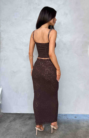 Back of girl wearing a brown lace midi skirt, matching crop top and nude heels.