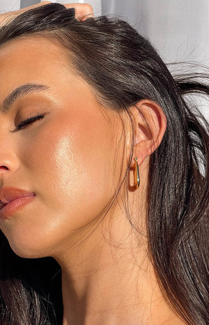 Girl with her eyes closed wearing the britney gold square hoop earrings.